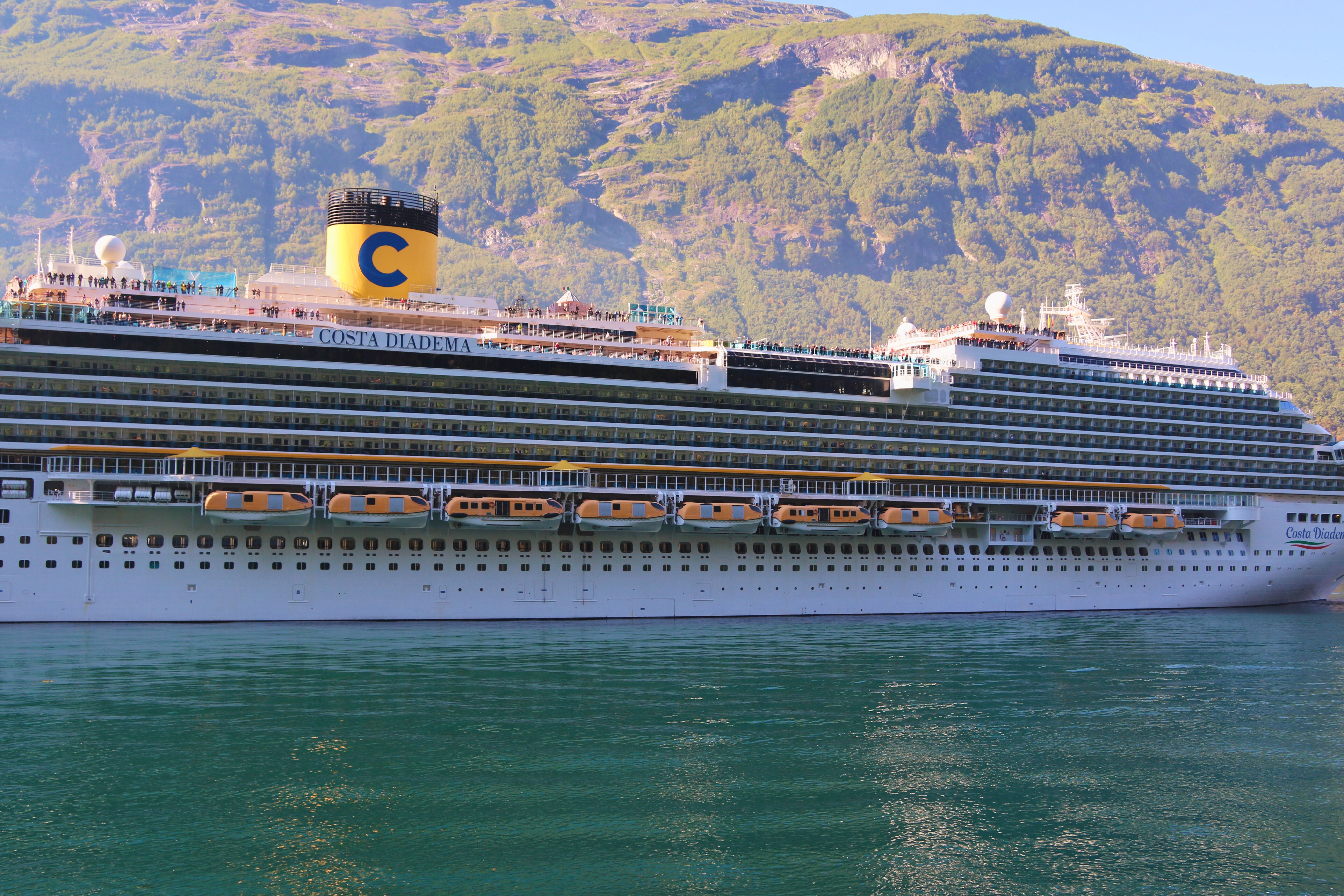 Cruise ship traveling through a Norwegian fjord surrounded by green mountains