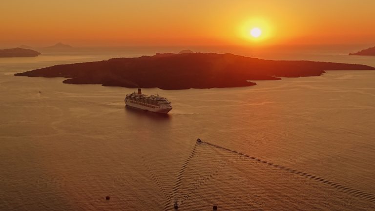 Cruise ship sailing near Santorini, Greece, at sunset