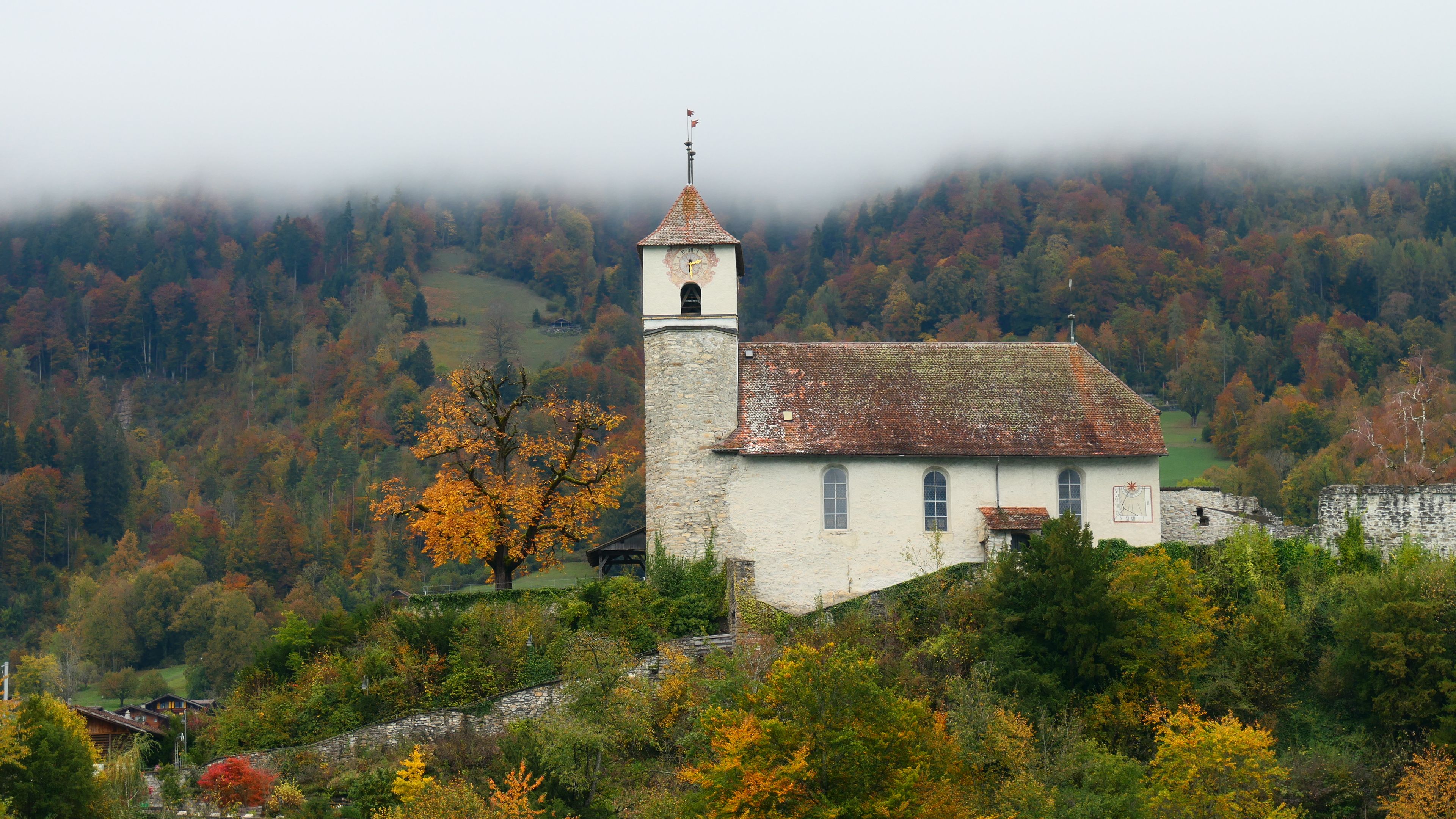 Historic church surrounded by vibrant fall foliage in Ringgenberg, Switzerland.